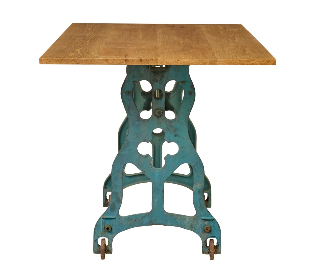 An industrial table featuring a rectangular natural oak top supported by a blue painted cast iron machine base on castors. View IV