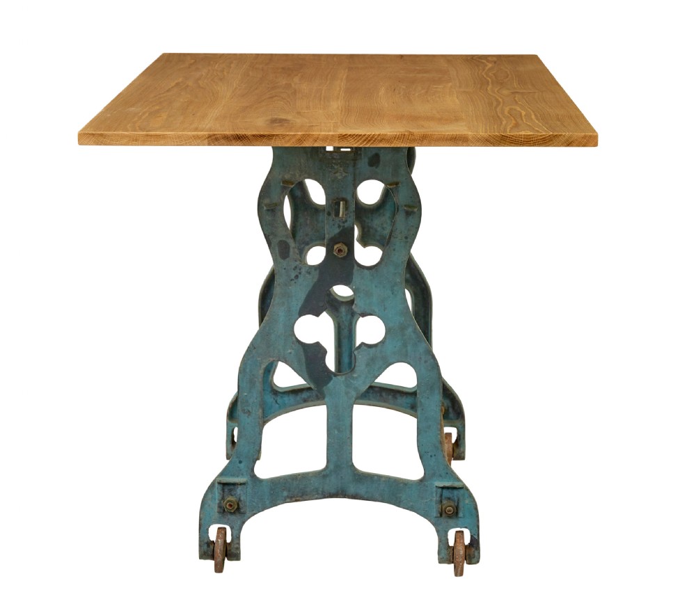 An industrial table featuring a rectangular natural oak top supported by a blue painted cast iron machine base on castors. View V