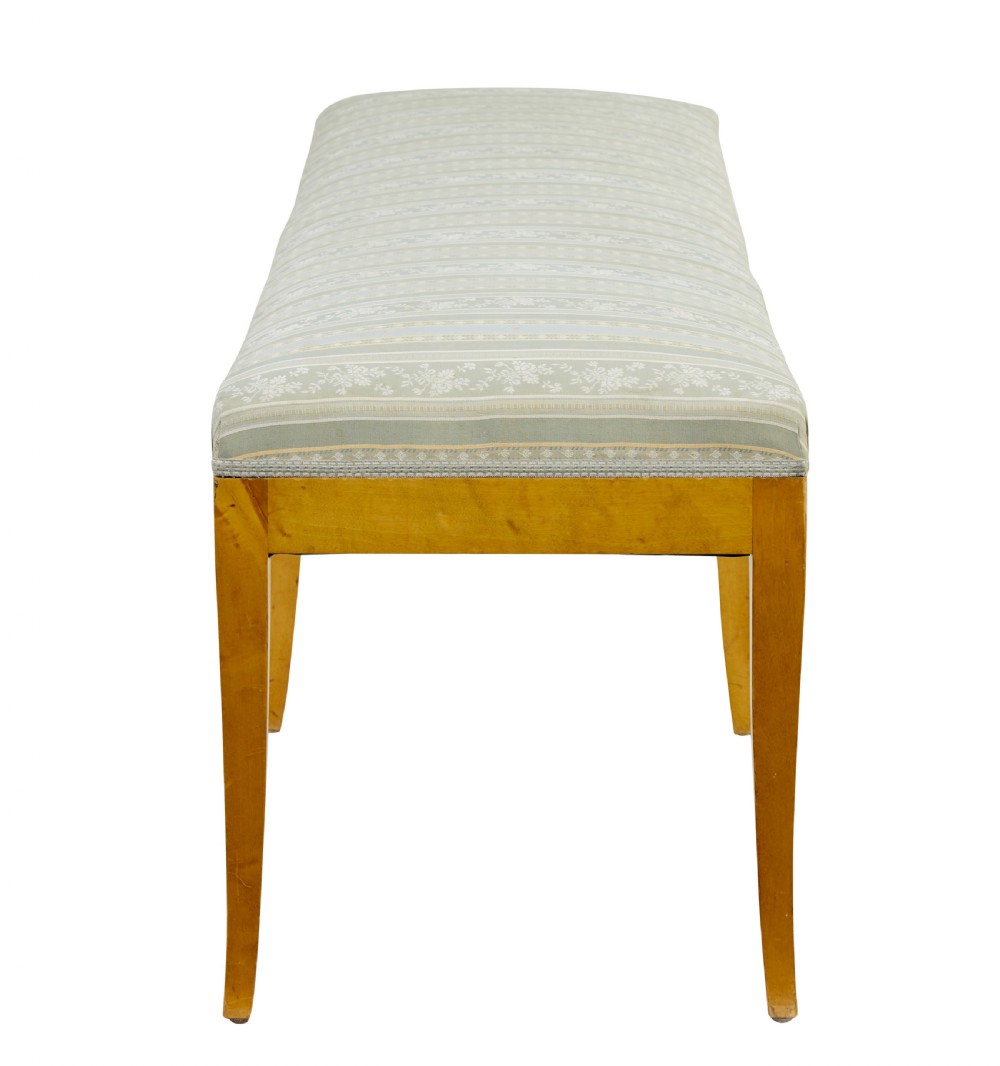 An early 20th-century Swedish long stool made of light honey-coloured birch wood with six square tapered legs and light blue striped upholstered seat. View V