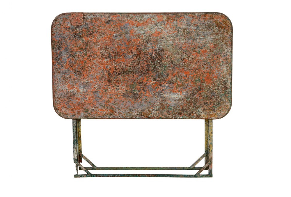 A rectangular folding metal garden table featuring a heavily distressed, multi-coloured painted surface and an X-frame iron base. View III