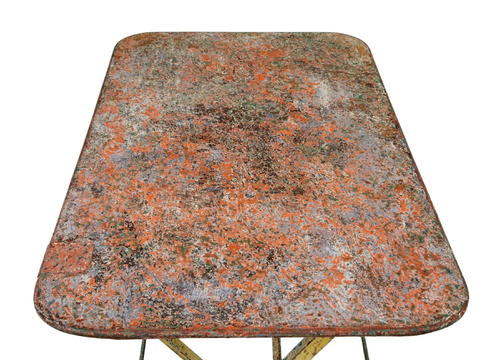 A rectangular folding metal garden table featuring a heavily distressed, multi-coloured painted surface and an X-frame iron base. View IV