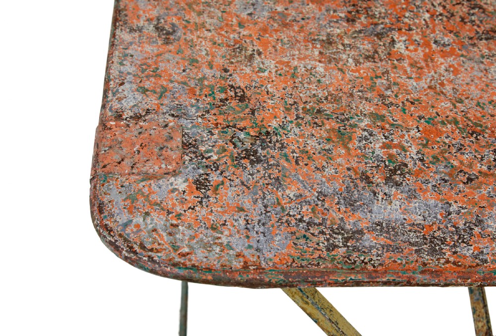 A rectangular folding metal garden table featuring a heavily distressed, multi-coloured painted surface and an X-frame iron base. View V