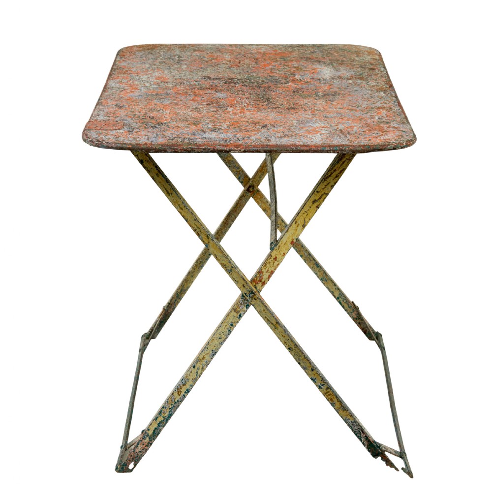 A rectangular folding metal garden table featuring a heavily distressed, multi-coloured painted surface and an X-frame iron base. View VII