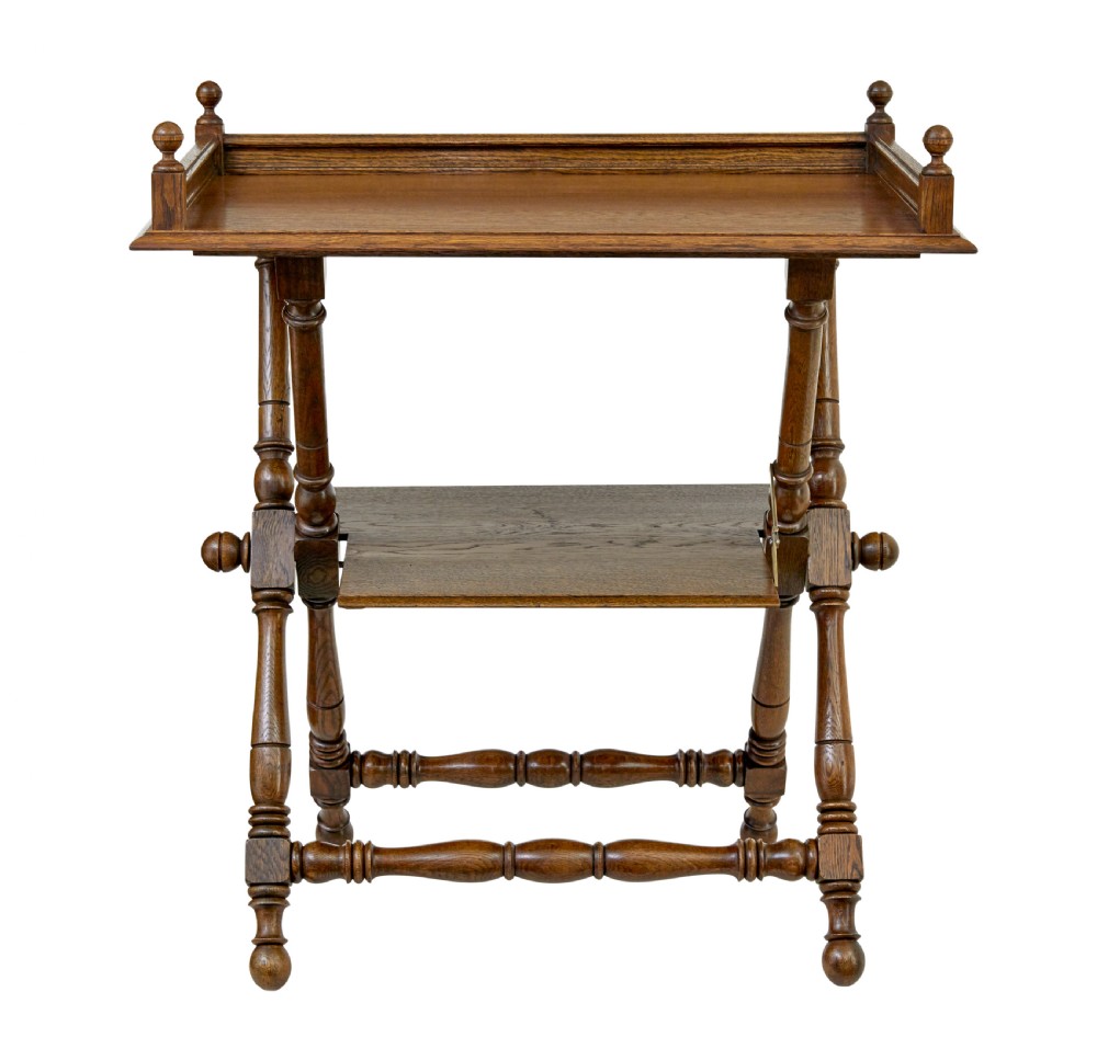 A 19th-century oak butlers tray table featuring a gallery-edged top tray with corner finials, a lower tiered shelf, and turned X-frame folding legs. View II