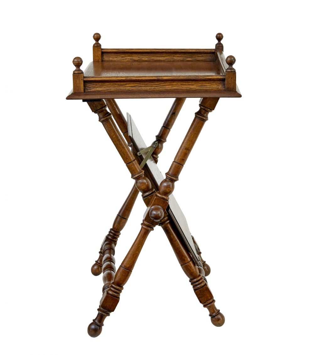 A 19th-century oak butlers tray table featuring a gallery-edged top tray with corner finials, a lower tiered shelf, and turned X-frame folding legs. View IV