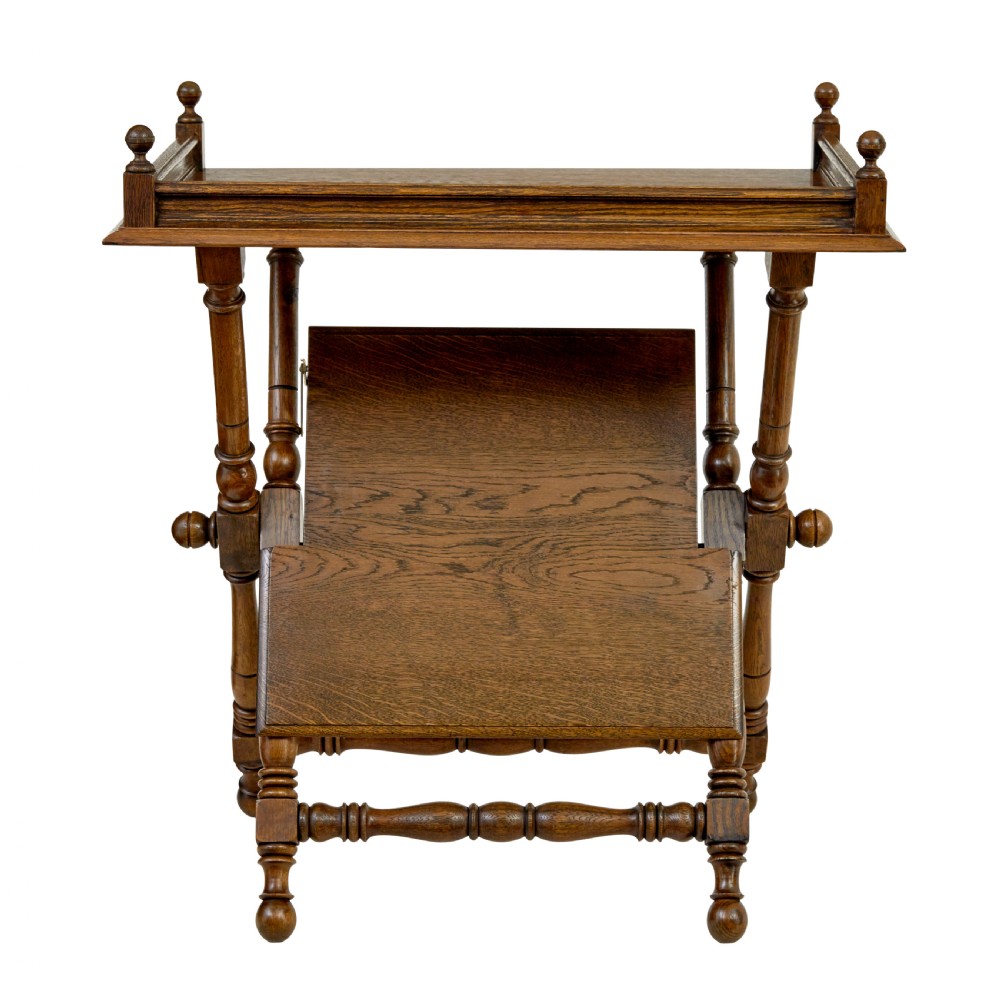 A 19th-century oak butlers tray table featuring a gallery-edged top tray with corner finials, a lower tiered shelf, and turned X-frame folding legs. View V