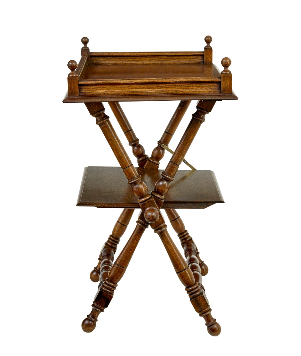 A 19th-century oak butlers tray table featuring a gallery-edged top tray with corner finials, a lower tiered shelf, and turned X-frame folding legs. View VI