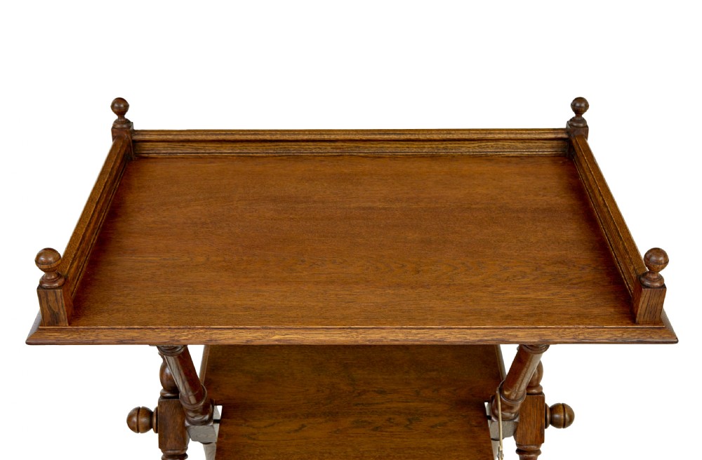 A 19th-century oak butlers tray table featuring a gallery-edged top tray with corner finials, a lower tiered shelf, and turned X-frame folding legs. View VIII