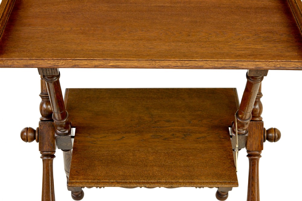 A 19th-century oak butlers tray table featuring a gallery-edged top tray with corner finials, a lower tiered shelf, and turned X-frame folding legs. View IX