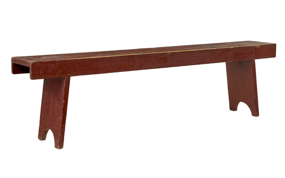 A long 19th-century Swedish pine bench painted in a distressed red finish with slab trestle legs featuring arched cut-outs.