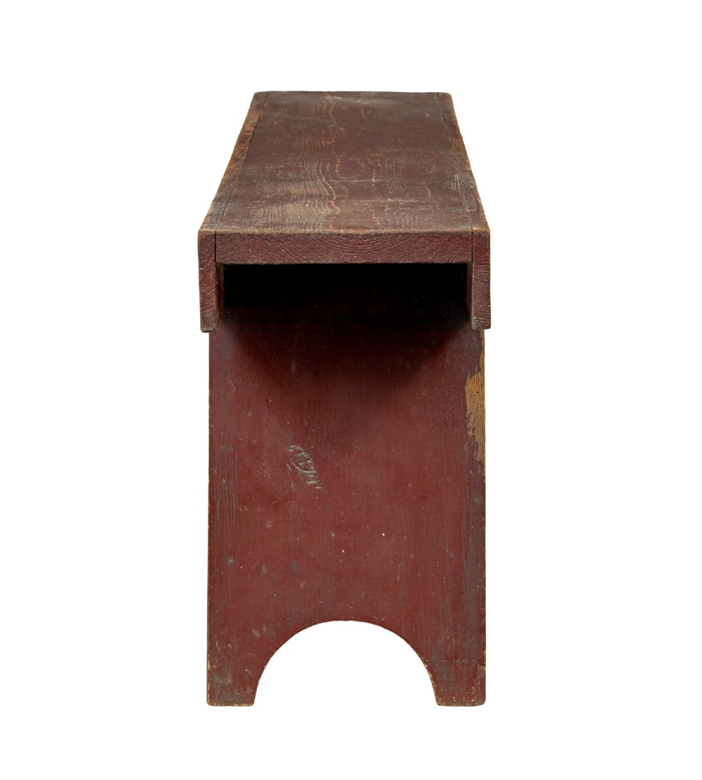A long 19th-century Swedish pine bench painted in a distressed red finish with slab trestle legs featuring arched cut-outs. View IV