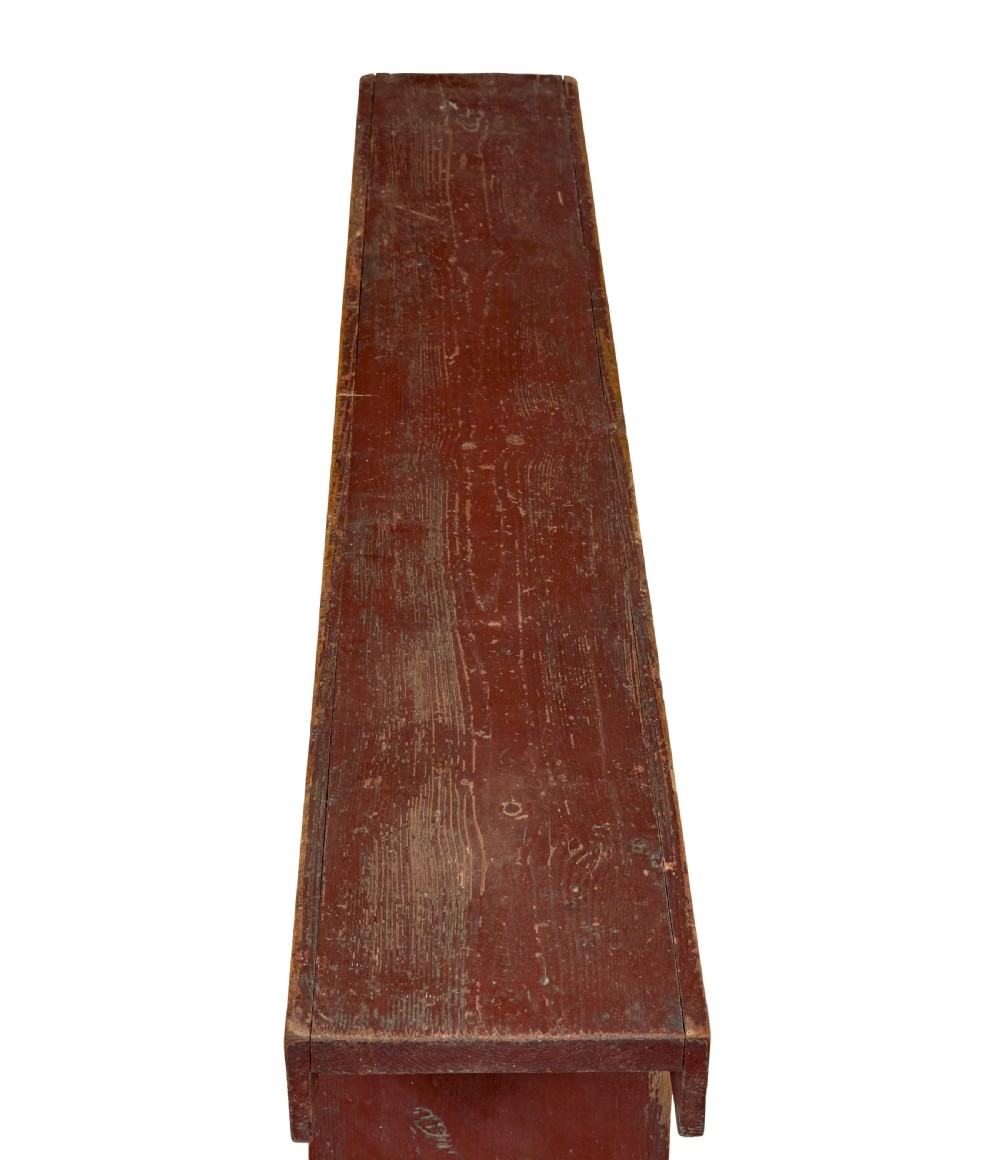 A long 19th-century Swedish pine bench painted in a distressed red finish with slab trestle legs featuring arched cut-outs. View VII