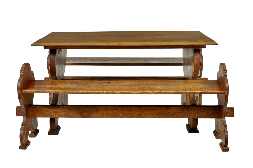 A 19th-century carved oak dining table flanked by two matching wooden benches with relief carvings on the trestle end supports. View II