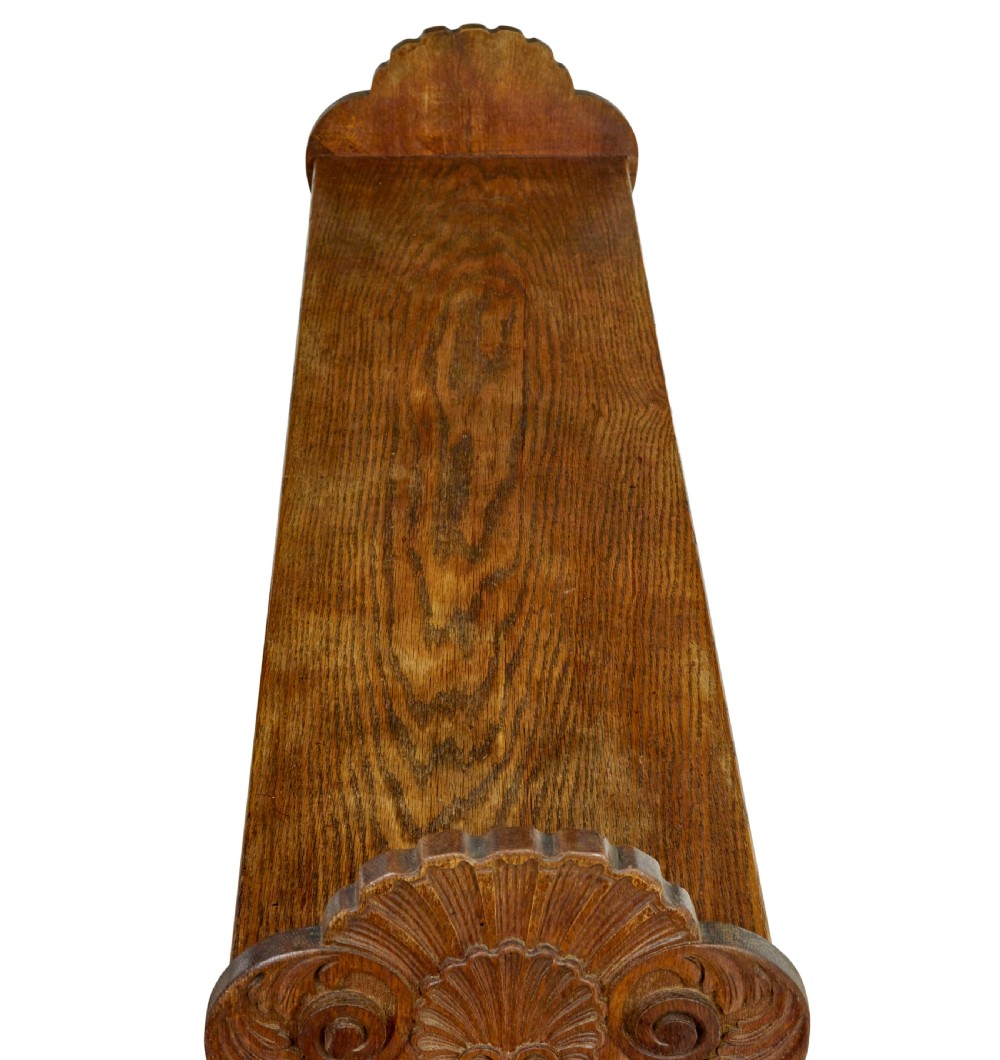 A 19th-century carved oak dining table flanked by two matching wooden benches with relief carvings on the trestle end supports. View VII