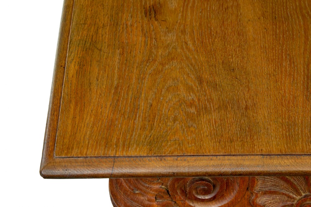 A 19th-century carved oak dining table flanked by two matching wooden benches with relief carvings on the trestle end supports. View IX