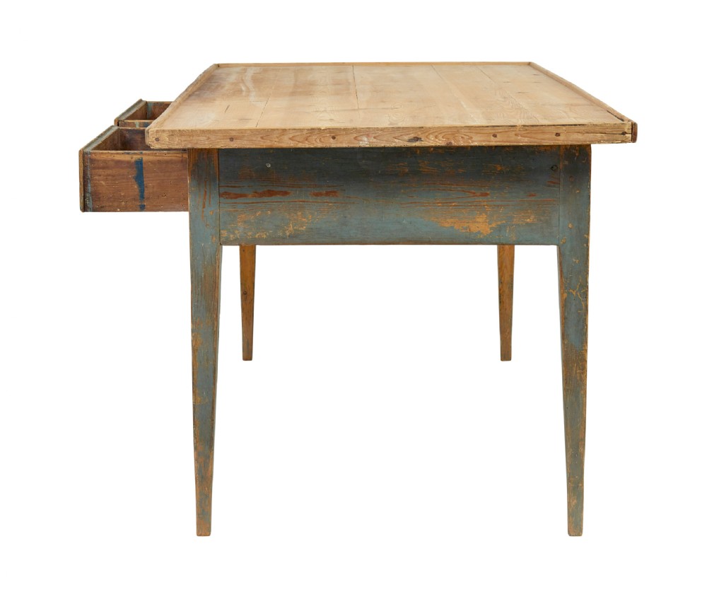 A mid 19th-century Swedish pine bakers table featuring two drawers, tapered square legs, and a distressed blue painted finish with a scrubbed wooden top. View IV