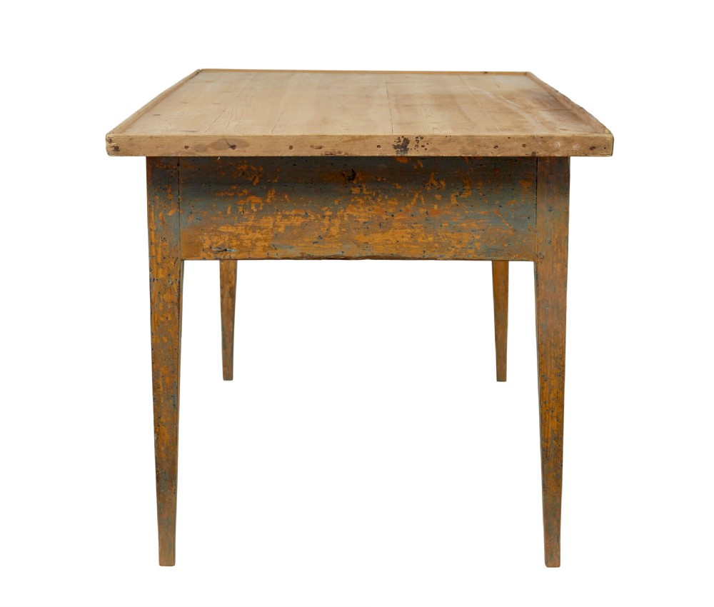 A mid 19th-century Swedish pine bakers table featuring two drawers, tapered square legs, and a distressed blue painted finish with a scrubbed wooden top. View VI
