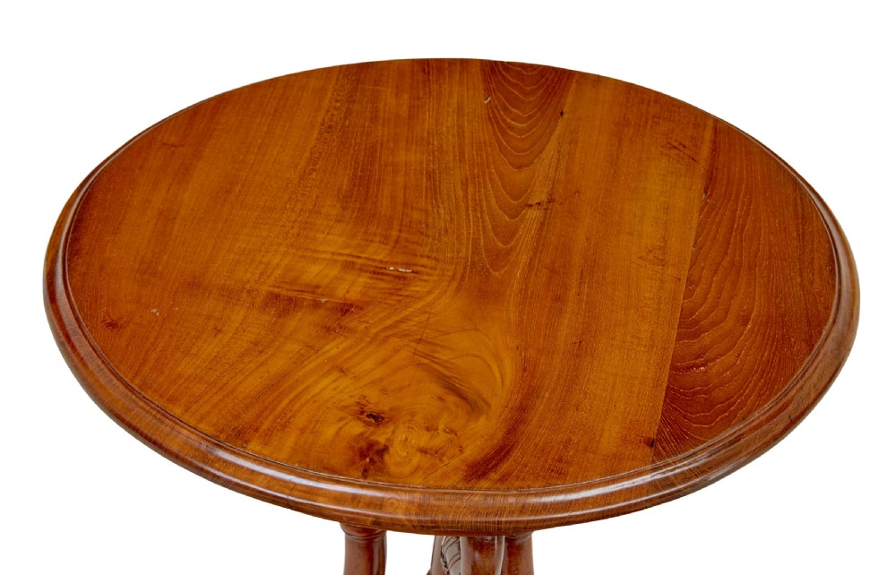 A circular carved teak side table featuring three curved legs and a central turned column on a triangular plinth base. View II