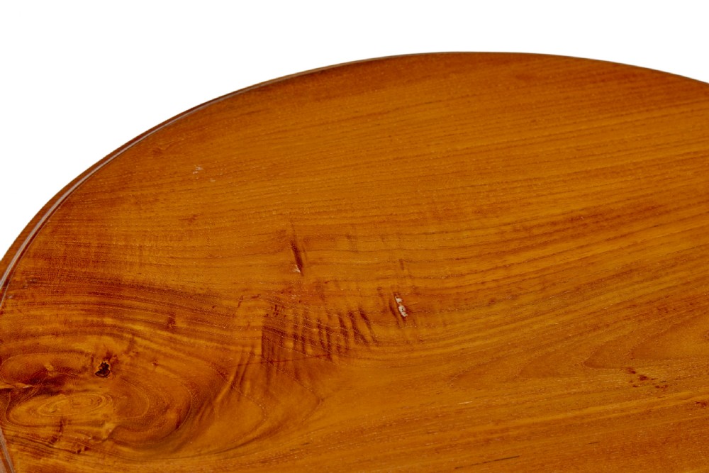 A circular carved teak side table featuring three curved legs and a central turned column on a triangular plinth base. View IV