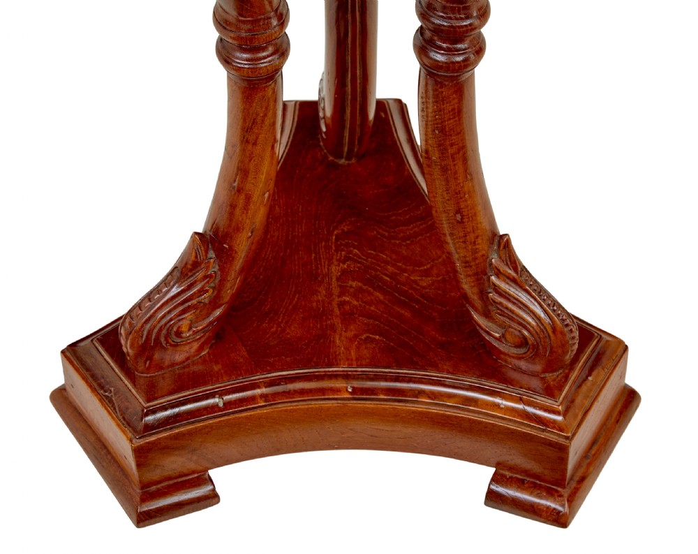 A circular carved teak side table featuring three curved legs and a central turned column on a triangular plinth base. View V