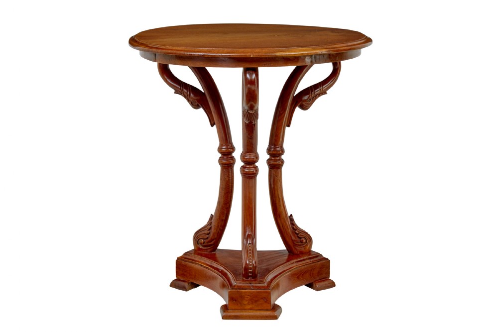 A circular carved teak side table featuring three curved legs and a central turned column on a triangular plinth base. View VII