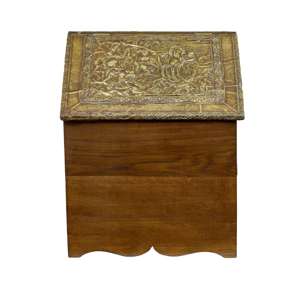 A 19th-century oak sloped-top storage box featuring an embossed brass lid panel depicting figures on horseback and a scalloped wooden base. View II