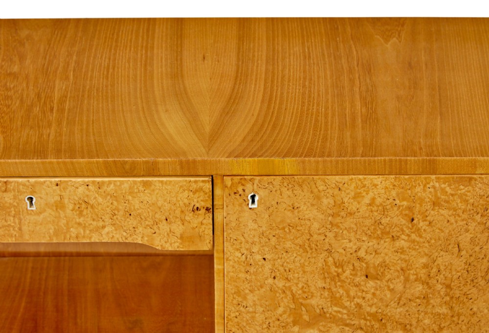 A low Scandinavian Art Deco open bookcase in golden burr elm with rounded upper corners, flanked cupboards, open central shelves, and sculpted feet. View IX