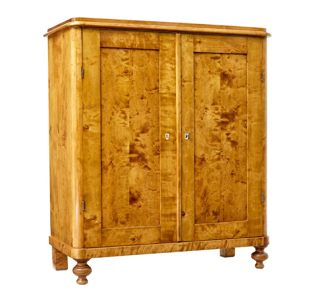 A 19th-century Swedish double-door cupboard crafted from highly figured golden birch timber with turned front feet.