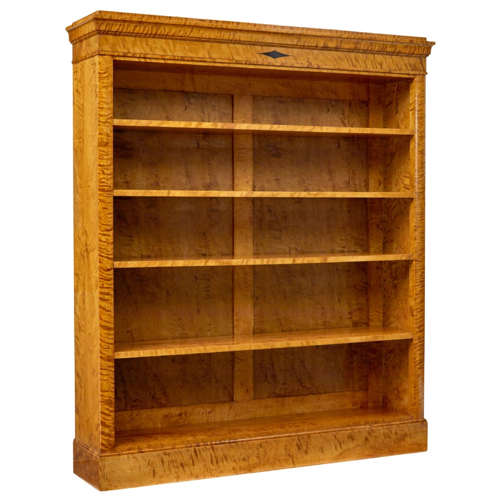 An early 20th-century Swedish Empire Revival open bookcase crafted from golden satin birch with a stepped cornice and ebonised diamond motif.