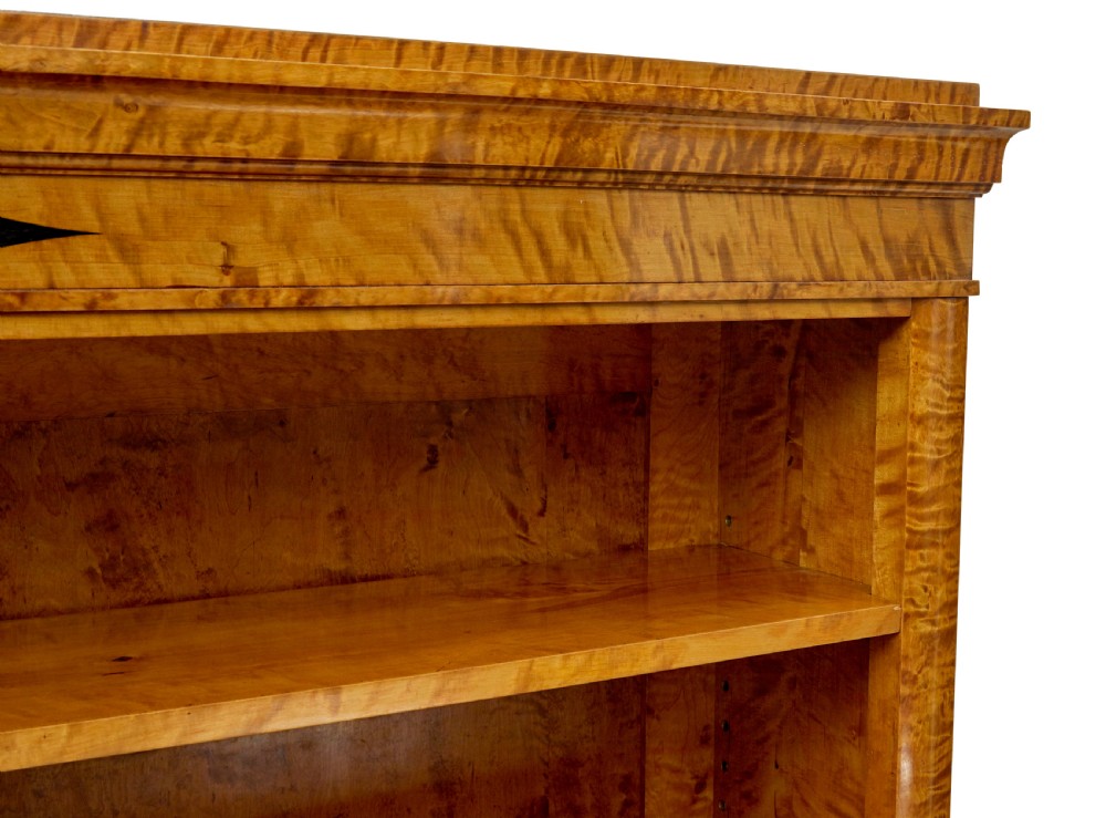 An early 20th-century Swedish Empire Revival open bookcase crafted from golden satin birch with a stepped cornice and ebonised diamond motif. View VIII