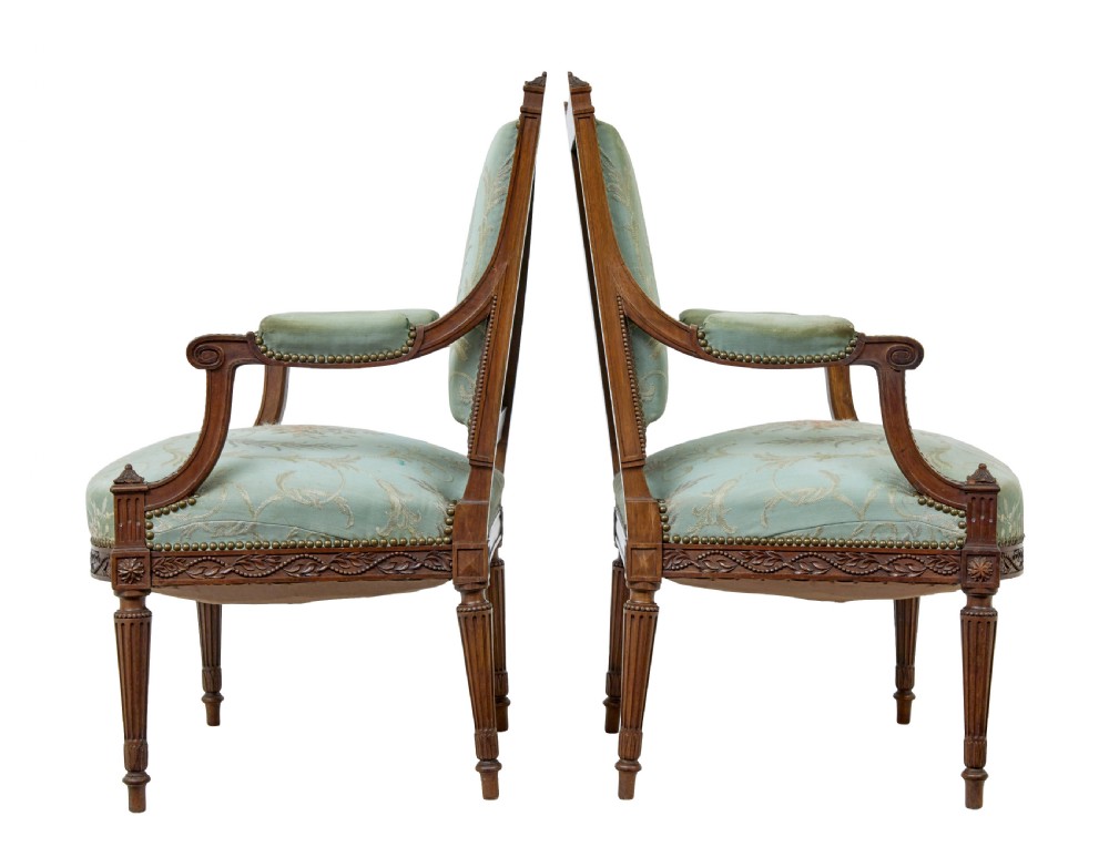 A pair of 19th-century French carved walnut armchairs featuring sage green floral tapestry upholstery, fluted legs, and padded armrests. View II