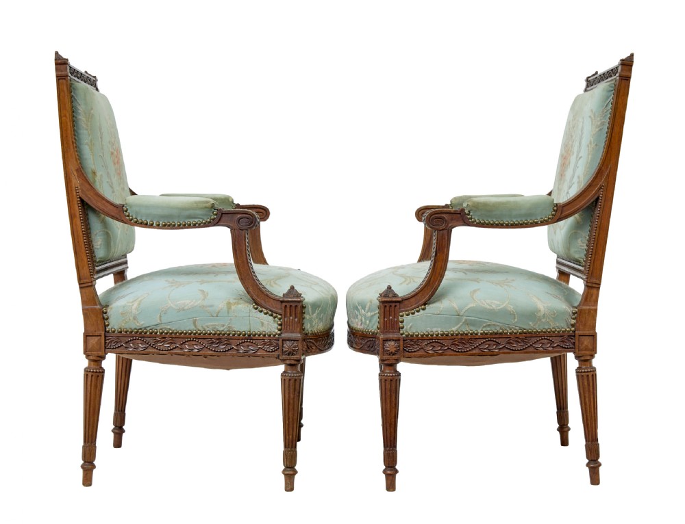 A pair of 19th-century French carved walnut armchairs featuring sage green floral tapestry upholstery, fluted legs, and padded armrests. View III