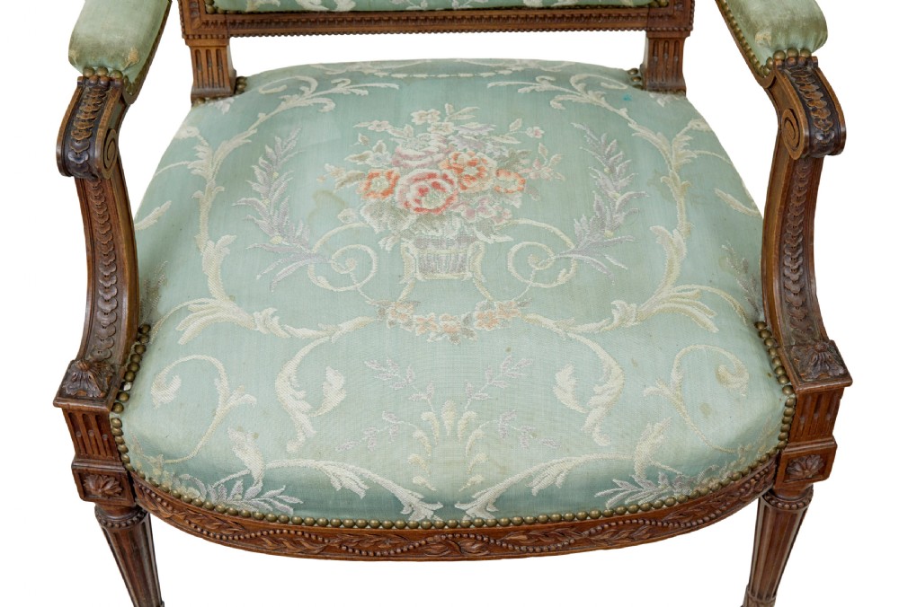 A pair of 19th-century French carved walnut armchairs featuring sage green floral tapestry upholstery, fluted legs, and padded armrests. View V