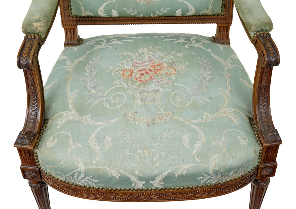 A pair of 19th-century French carved walnut armchairs featuring sage green floral tapestry upholstery, fluted legs, and padded armrests. View VI