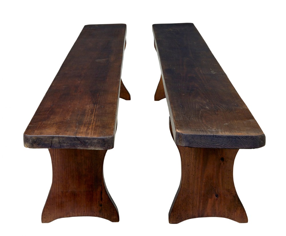 A pair of long early twentieth-century dark pine wooden benches with trestle-style legs. View II