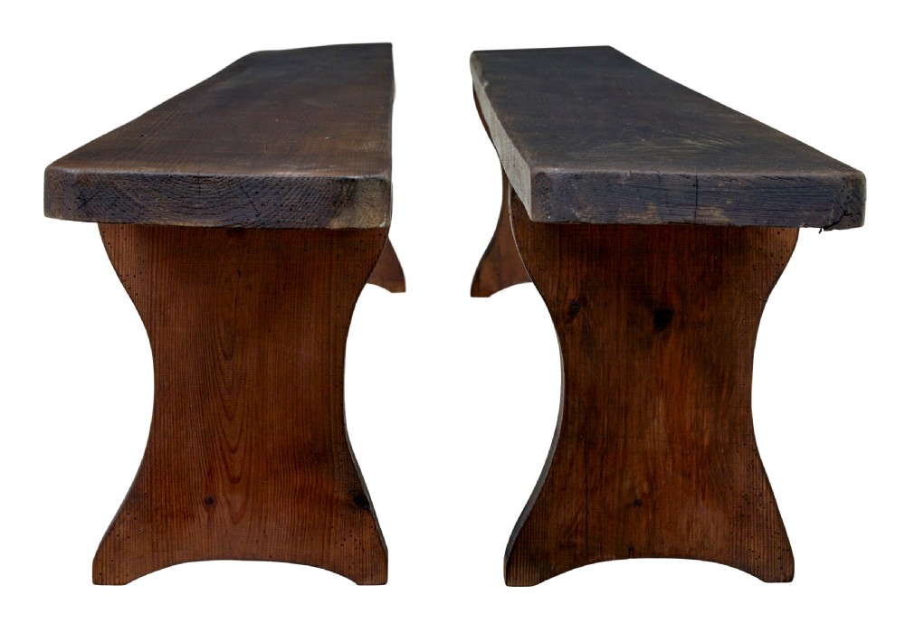 A pair of long early twentieth-century dark pine wooden benches with trestle-style legs. View V