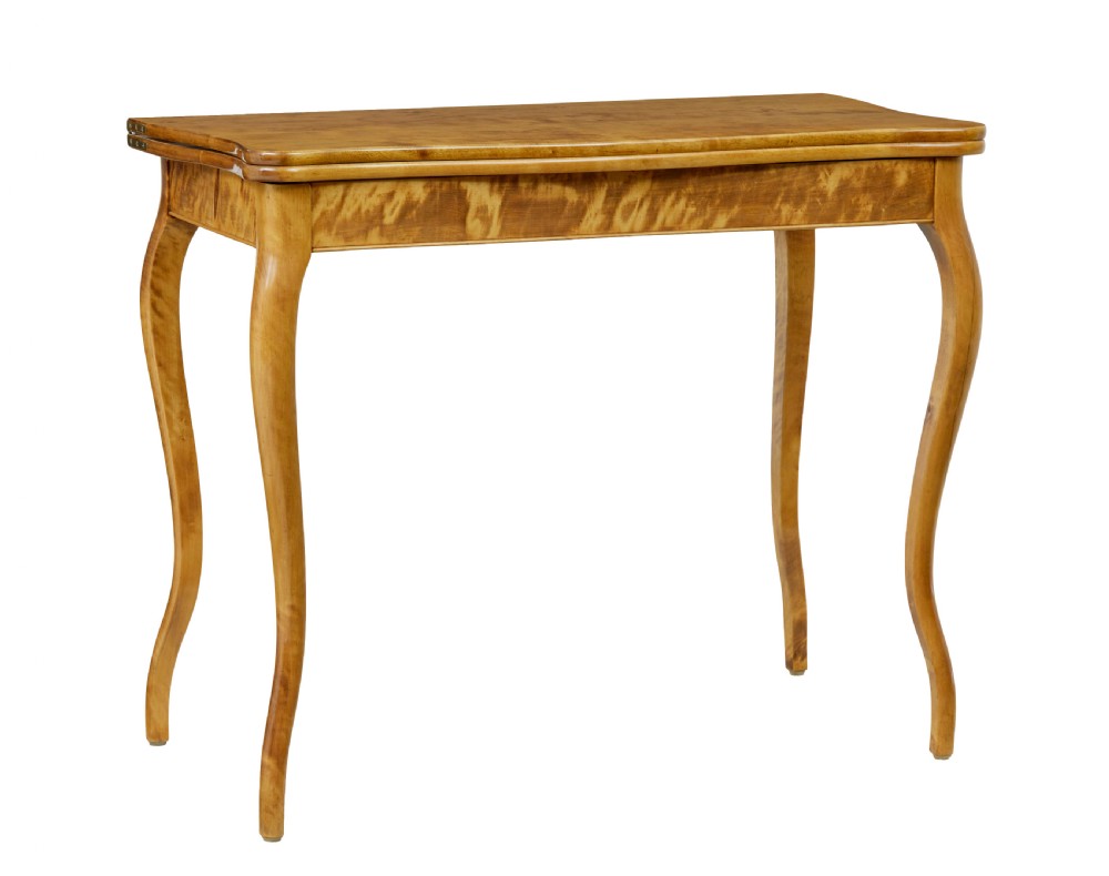 A 19th-century Swedish Rococo Revival tea table crafted from highly figured golden birch with cabriole legs and a fold-over top.