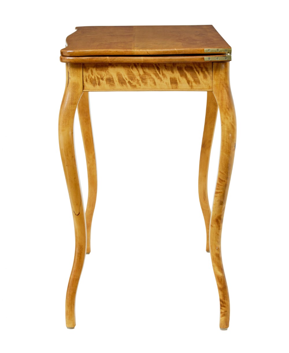 A 19th-century Swedish Rococo Revival tea table crafted from highly figured golden birch with cabriole legs and a fold-over top. View V