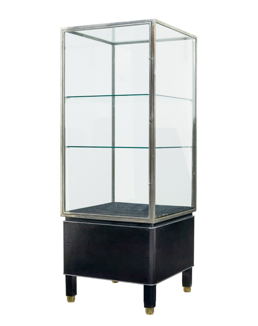 A tall rectangular Art Deco display cabinet featuring transparent glass sides and glass shelves within a thin steel frame, set upon a black leather-clad base with short brass-tipped legs.