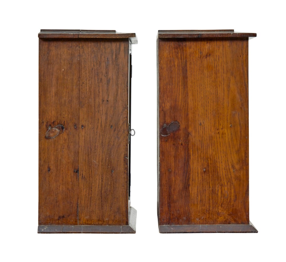 A pair of antique warm brown oak tabletop cabinets featuring glazed doors, brass keyhole escutcheons, and two internal drawers with decorative brass handles. View V