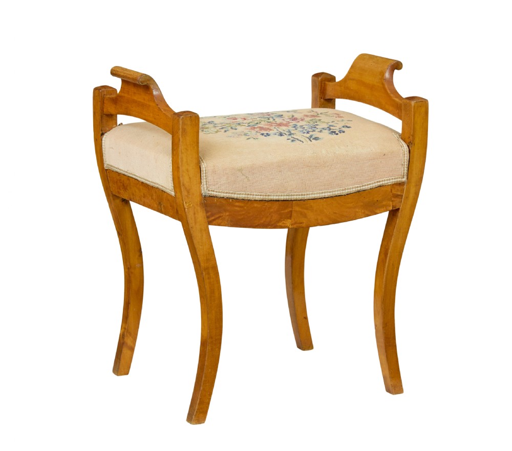 A mid-19th-century Swedish birch Empire stool featuring curved sabre legs, side handles, and a needlepoint upholstered seat with floral embroidery. View II