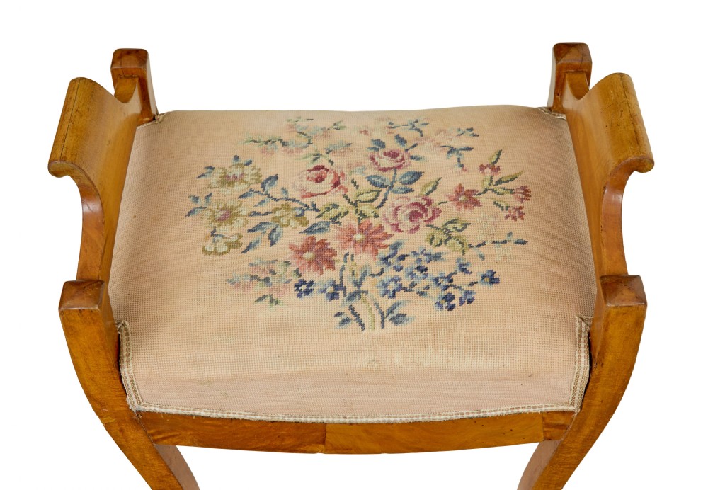 A mid-19th-century Swedish birch Empire stool featuring curved sabre legs, side handles, and a needlepoint upholstered seat with floral embroidery. View VII