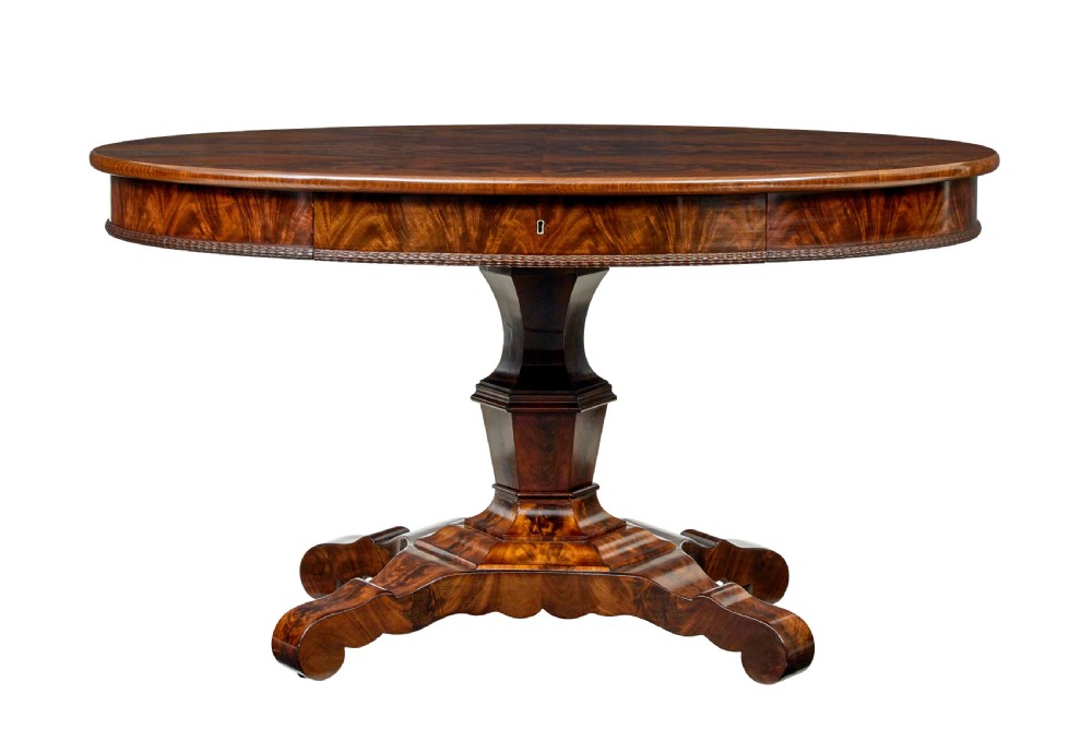 A circular mid-19th-century flame mahogany centre table featuring a frieze drawer, supported by an octagonal pedestal stem and a quadruped scroll-foot base.