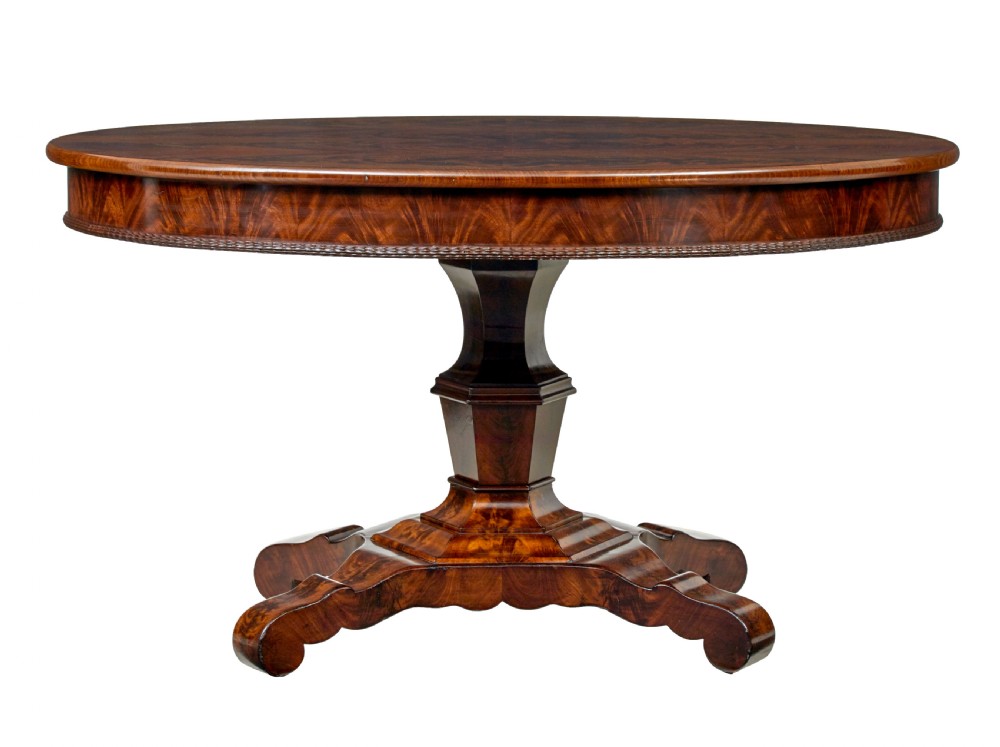 A circular mid-19th-century flame mahogany centre table featuring a frieze drawer, supported by an octagonal pedestal stem and a quadruped scroll-foot base. View IV