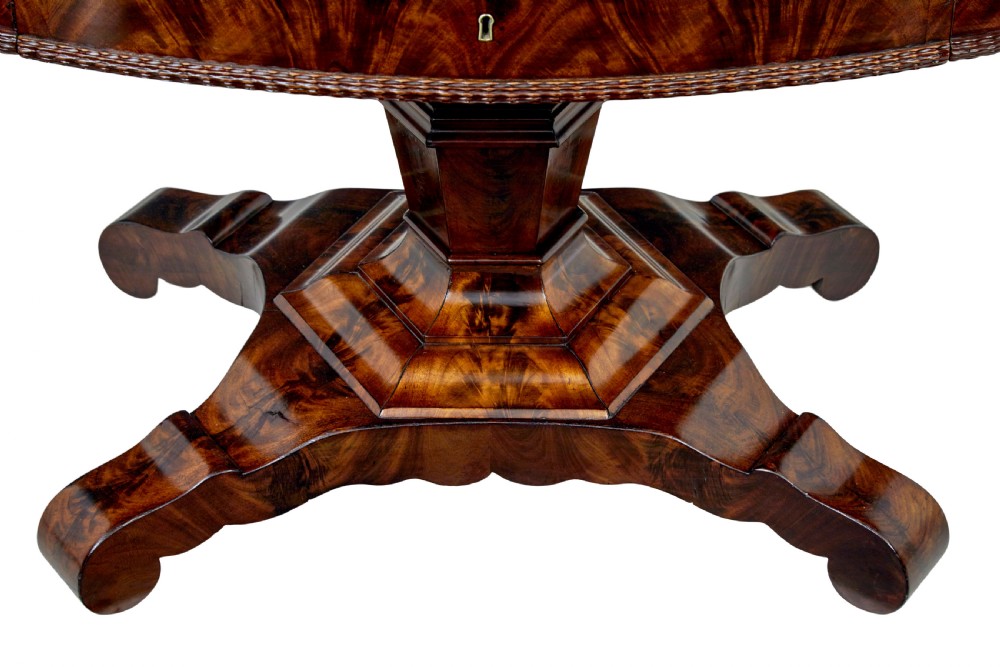 A circular mid-19th-century flame mahogany centre table featuring a frieze drawer, supported by an octagonal pedestal stem and a quadruped scroll-foot base. View IX