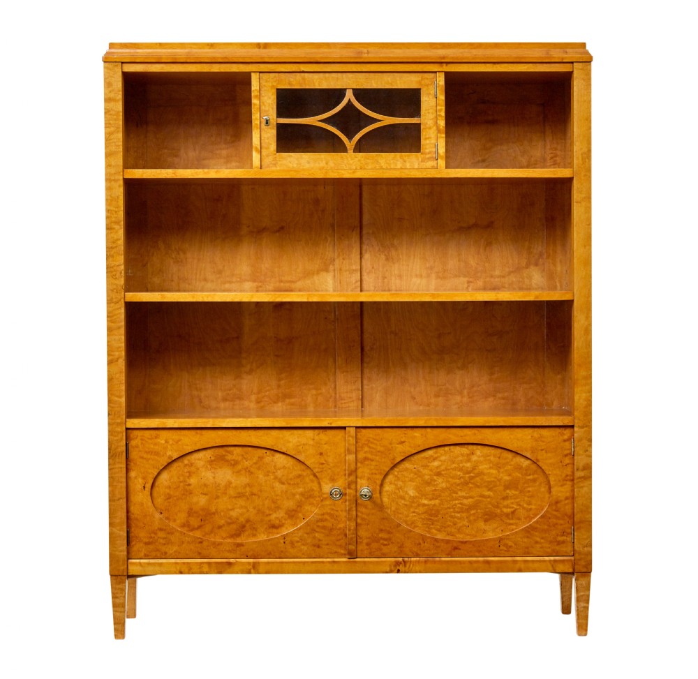 An early 20th-century Swedish Grace satin birch open bookcase featuring a small glazed upper door, open shelving, and a double-door lower cabinet with oval panelling. View III
