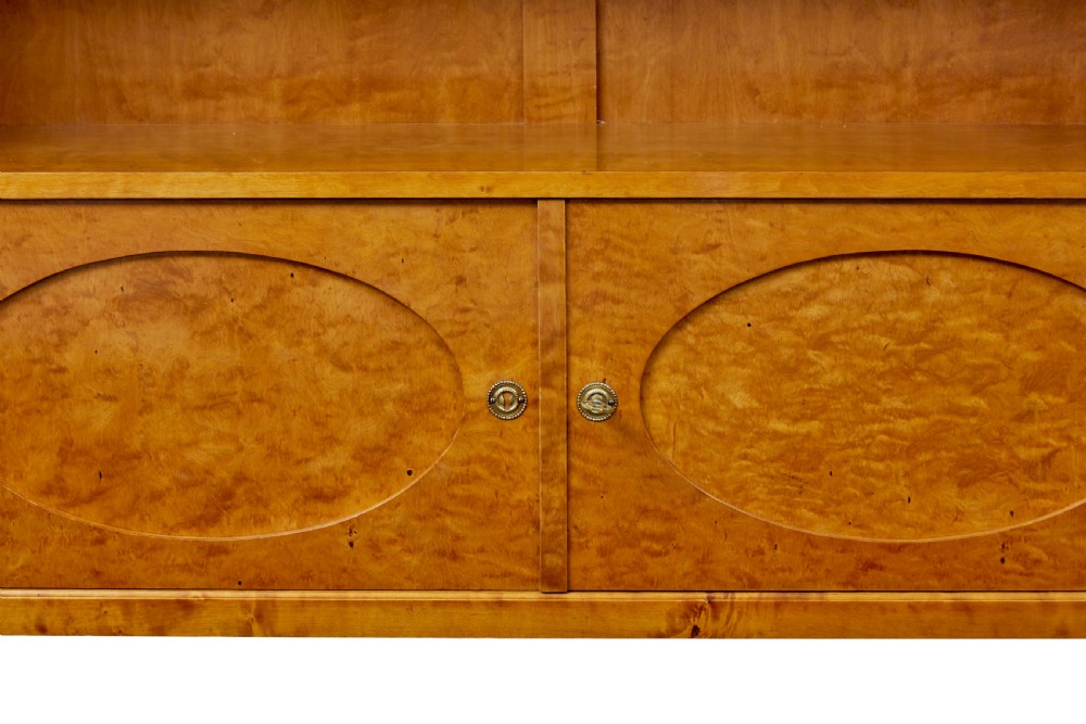 An early 20th-century Swedish Grace satin birch open bookcase featuring a small glazed upper door, open shelving, and a double-door lower cabinet with oval panelling. View VIII