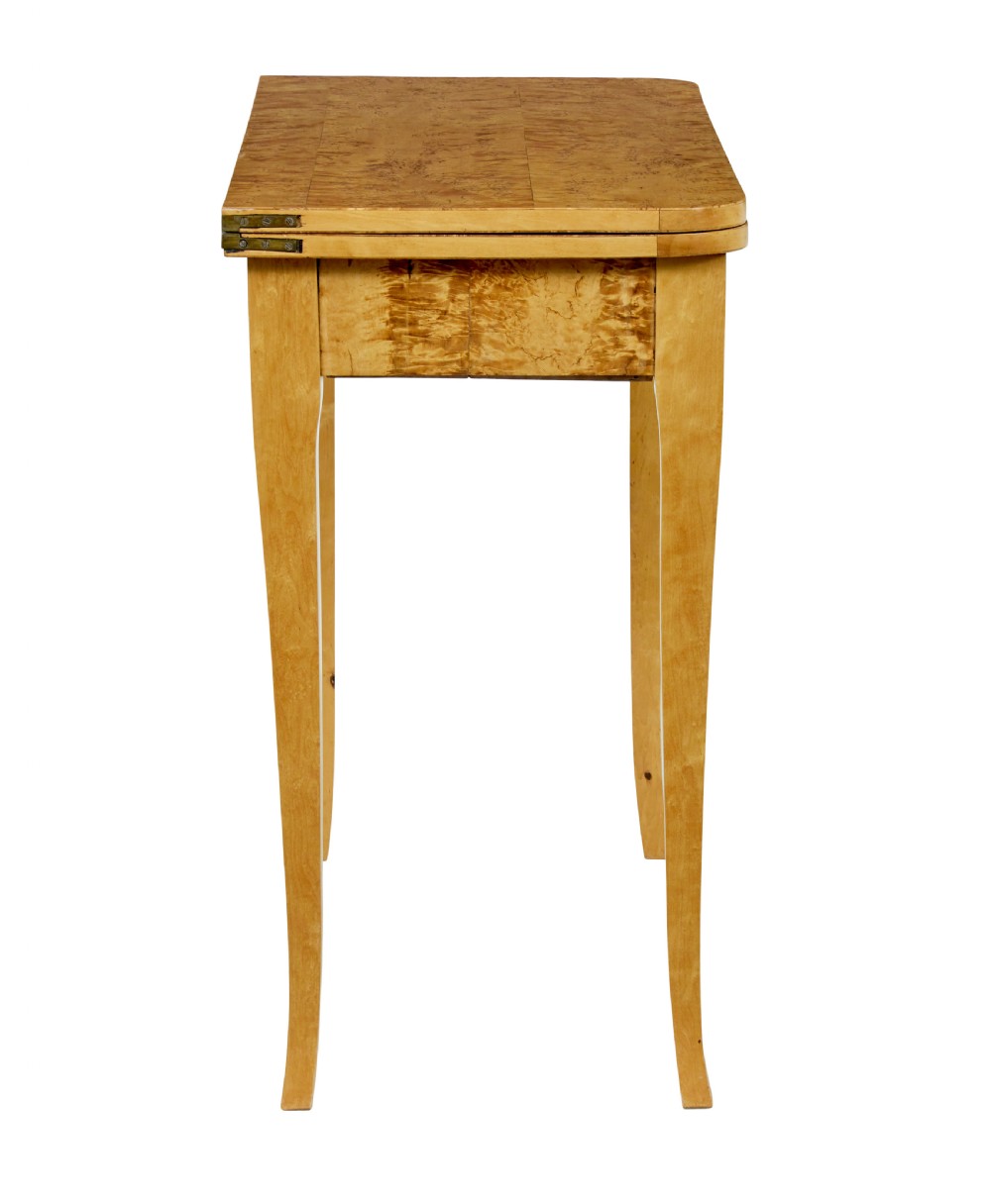A 19th-century Swedish tea table constructed from warm burr birch veneer featuring slender tapered legs and a folding rectangular top. View X
