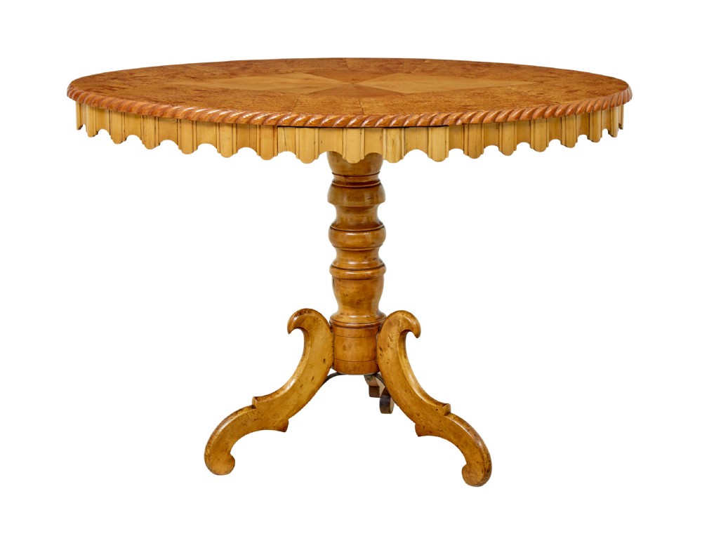 A nineteenth-century oval occasional table crafted from inlaid burr birch with a scalloped apron, turned central pedestal, and four carved scrolled legs. View II