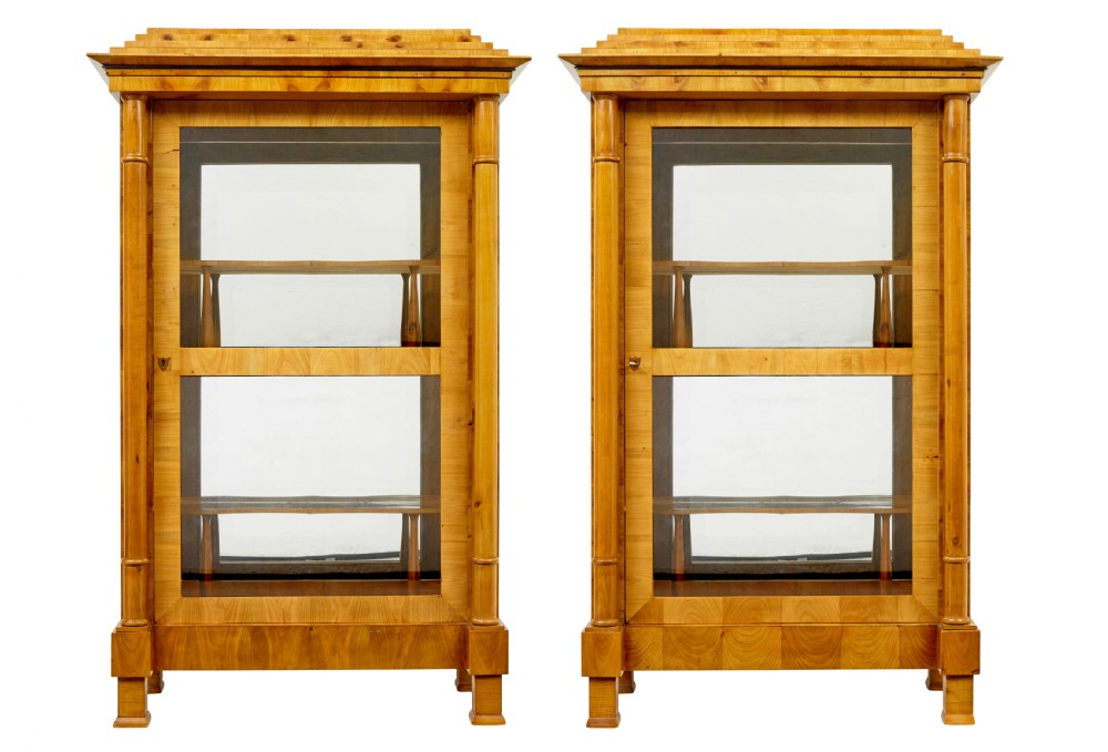 A matching pair of Biedermeier elm display cabinets with glazed doors, side columns, and stepped cornices.